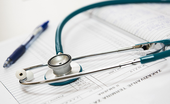 Image of a stethoscope and blue ink pen on top of a medical chart.